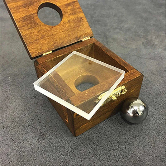 כדור מתכת חודר זכוכית בקופסה מעץ